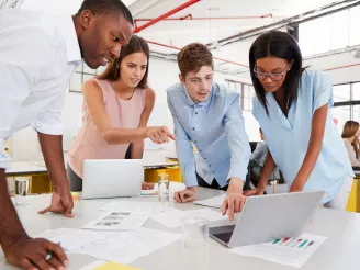 Small workgroup meeting with printed documents and laptops